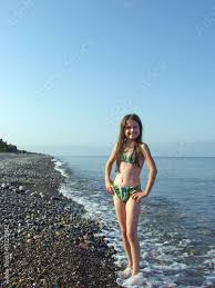 Little girl in bikini posing on a deserted pebble beach Stock 写真 ...